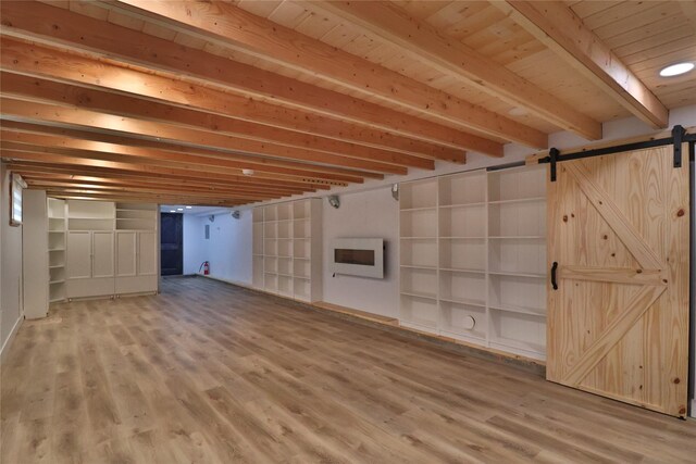 basement with heating unit, hardwood / wood-style floors, built in shelves, and a barn door