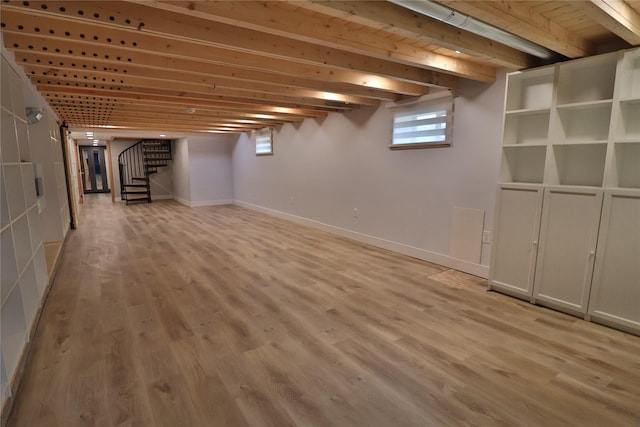 basement with light wood-style floors, stairway, and baseboards