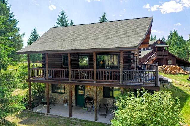 87 Badger Trl, Eureka, MT 59917 - back of house featuring log siding, a patio area, a deck, a shingled roof, and a lawn