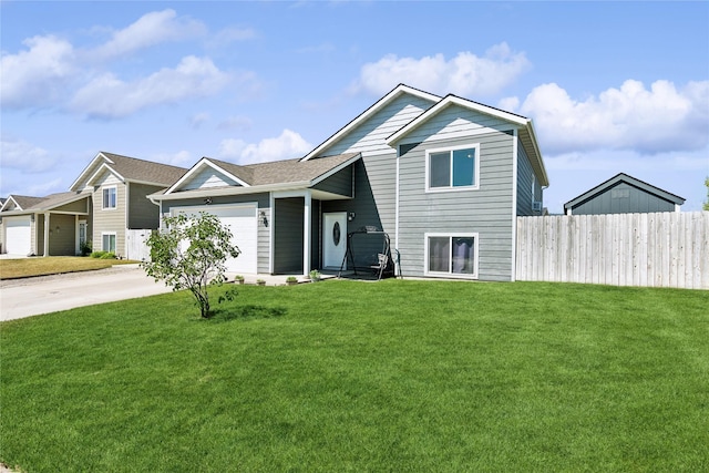 split level home featuring driveway, a front yard, a garage, and fence