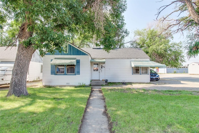 view of front of house featuring a shingled roof, a front yard, and crawl space