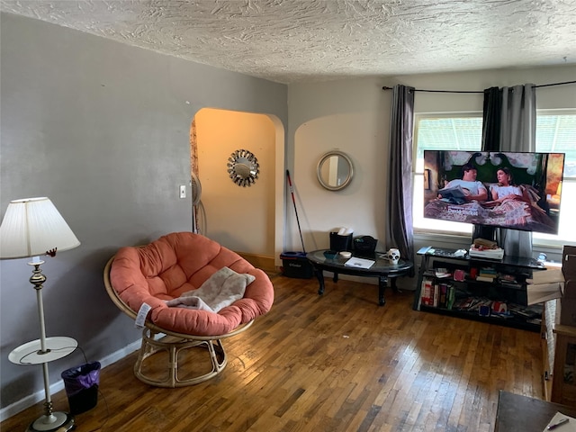 living area featuring wood-type flooring and a textured ceiling