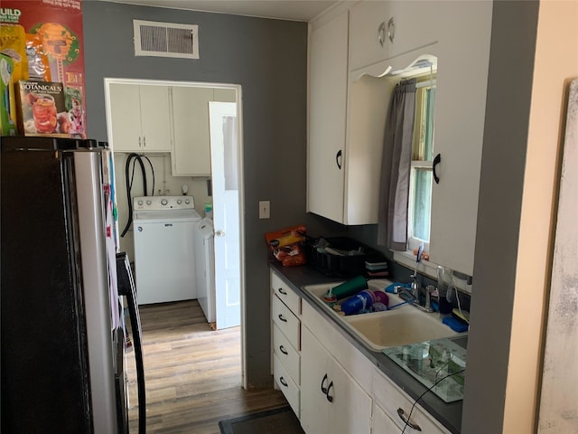 kitchen with white cabinetry, sink, stainless steel fridge, and washing machine and dryer