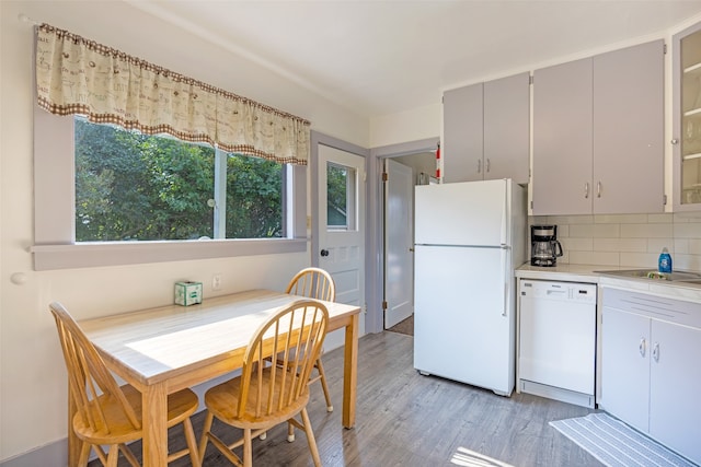 kitchen featuring gray cabinetry, light hardwood / wood-style floors, white appliances, and backsplash