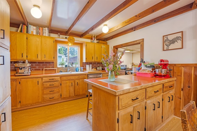 kitchen with beam ceiling, light hardwood / wood-style flooring, stainless steel dishwasher, sink, and a kitchen bar