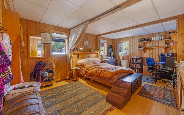 bedroom featuring wood walls and a drop ceiling