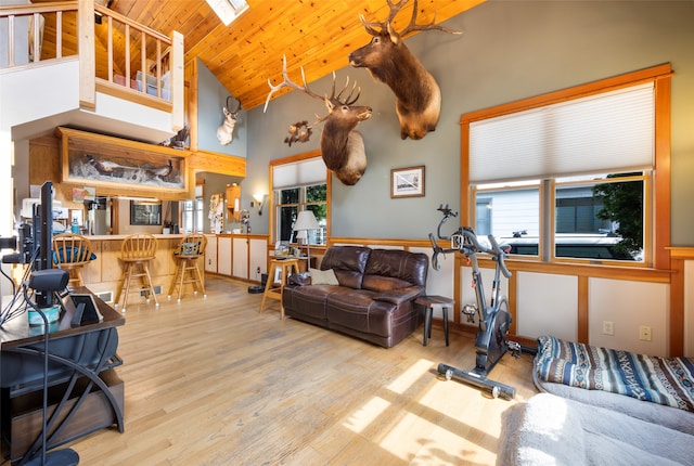 living room with light hardwood / wood-style floors, wooden ceiling, a healthy amount of sunlight, and high vaulted ceiling