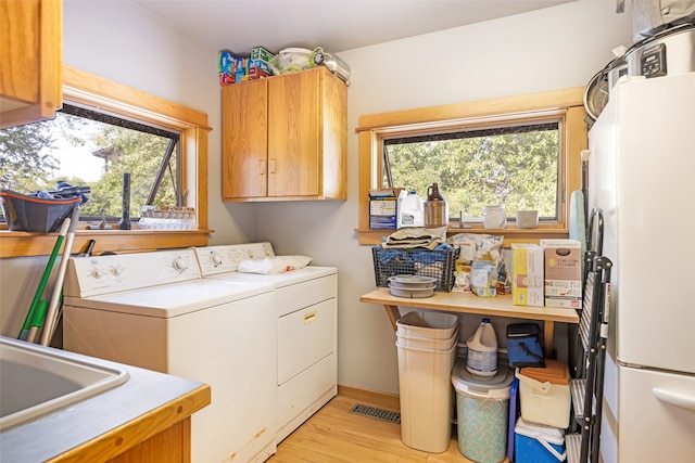 washroom featuring washer and clothes dryer, sink, light wood-type flooring, and cabinets