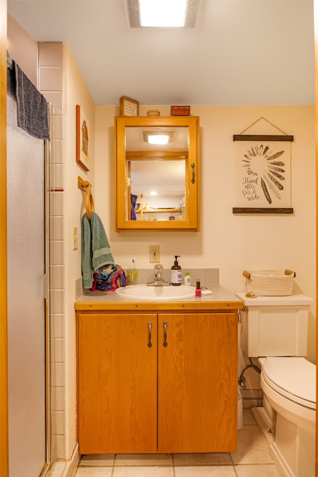 bathroom featuring a shower with shower door, vanity, tile patterned flooring, and toilet