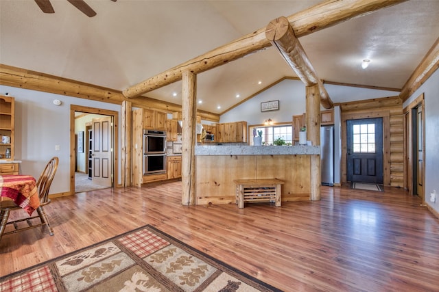 kitchen with lofted ceiling with beams, light wood-style flooring, light countertops, appliances with stainless steel finishes, and rustic walls