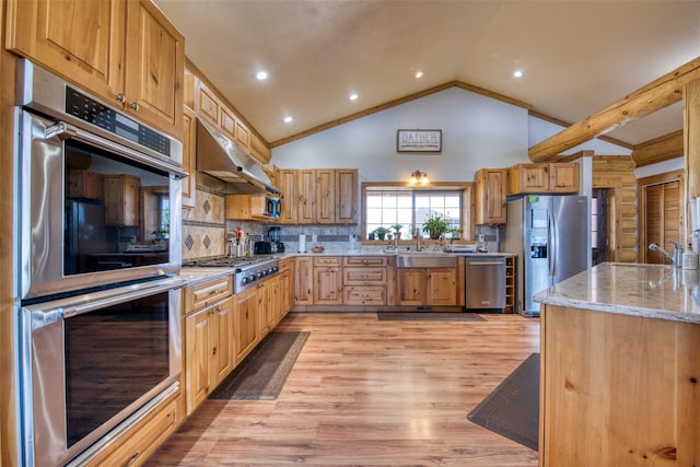 kitchen with light wood finished floors, tasteful backsplash, appliances with stainless steel finishes, light stone counters, and under cabinet range hood