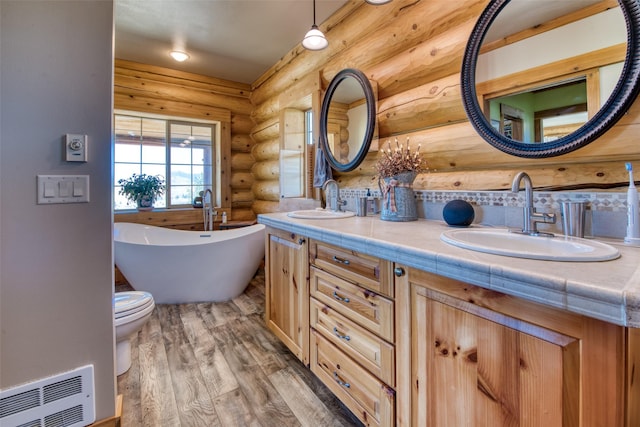 bathroom with a soaking tub, visible vents, a sink, and wood finished floors