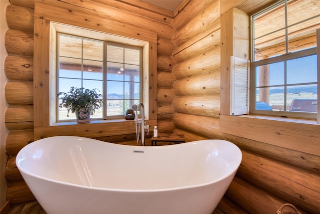 full bath with a soaking tub, rustic walls, and plenty of natural light