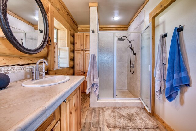 full bathroom featuring a stall shower, decorative backsplash, wood finished floors, and vanity