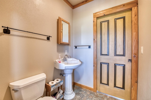 bathroom featuring toilet, baseboards, and a sink