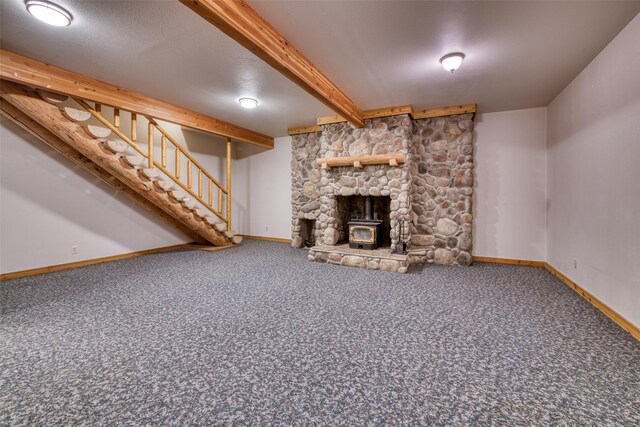 unfurnished living room featuring carpet floors, baseboards, stairs, beam ceiling, and a wood stove