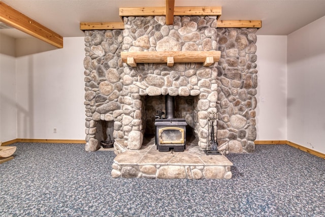 unfurnished living room with carpet, a wood stove, beamed ceiling, and baseboards