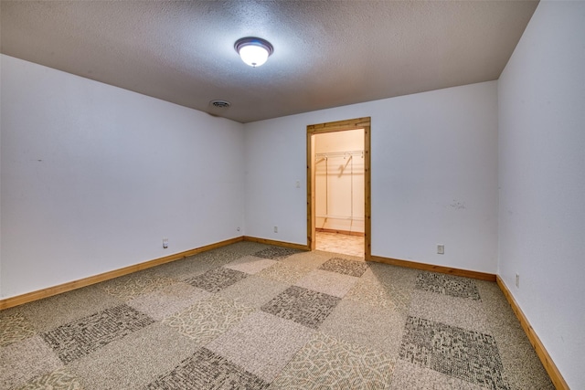 empty room featuring a textured ceiling, baseboards, visible vents, and light colored carpet