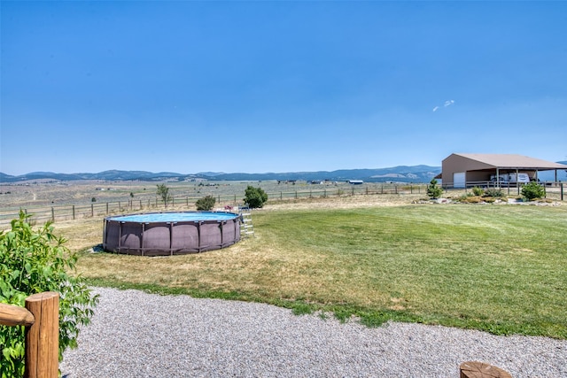 view of yard featuring a fenced in pool, a rural view, a mountain view, and fence