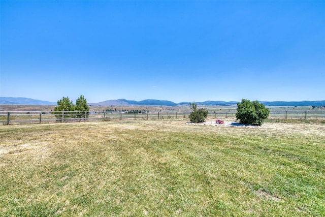 view of yard with a rural view, fence, and a mountain view