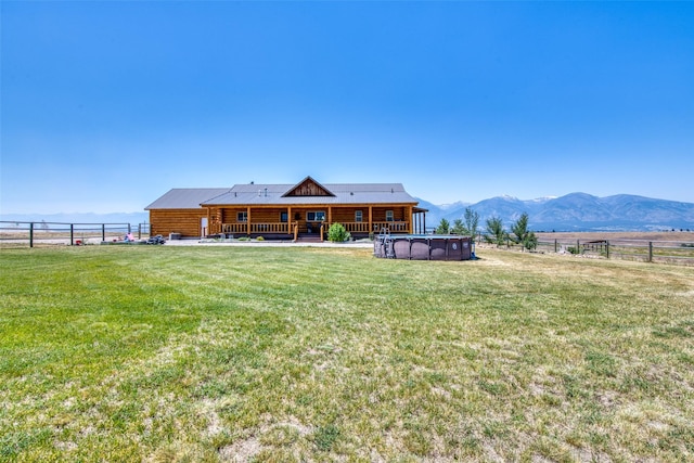 back of property with a fenced in pool, a yard, fence, metal roof, and a mountain view