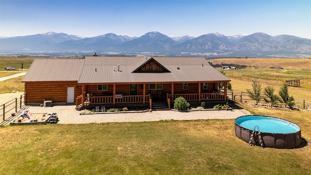 back of house featuring an outdoor pool, metal roof, fence, a yard, and central AC