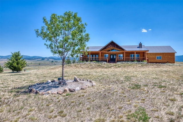 rear view of property featuring covered porch, metal roof, a chimney, and a mountain view