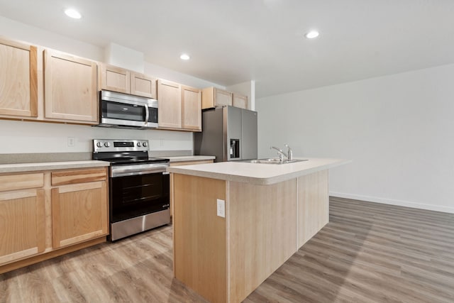 kitchen featuring an island with sink, stainless steel appliances, light hardwood / wood-style floors, and sink