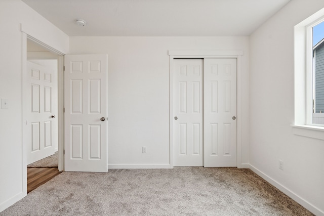 unfurnished bedroom featuring light carpet and a closet