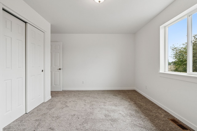 unfurnished bedroom with a closet, multiple windows, and carpet floors