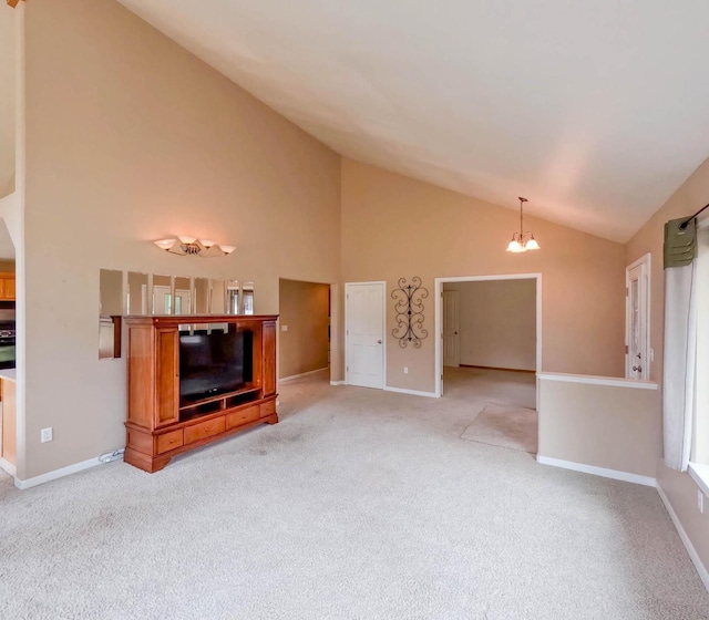 unfurnished living room with an inviting chandelier, high vaulted ceiling, and light colored carpet