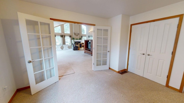 bedroom with a closet, light carpet, and french doors