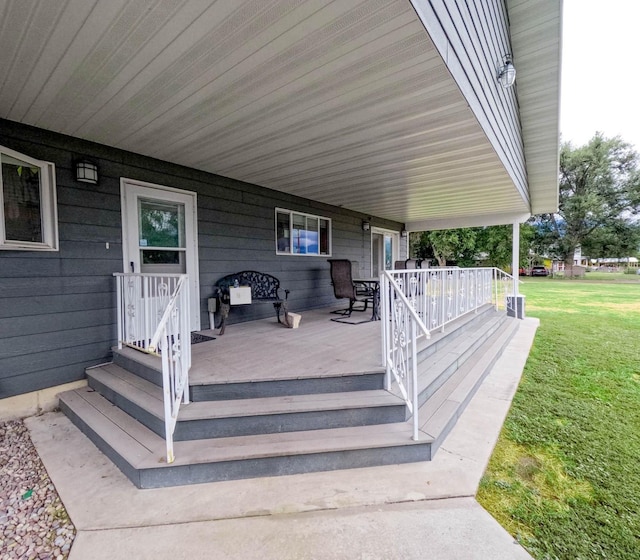 wooden terrace with a lawn and a porch