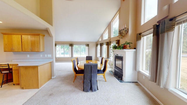 carpeted dining room with a towering ceiling and a fireplace