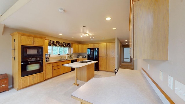 kitchen with light brown cabinetry, sink, a kitchen bar, a center island, and black appliances