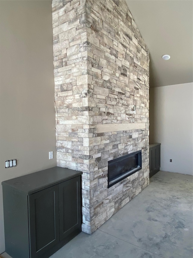 unfurnished living room featuring lofted ceiling and a stone fireplace