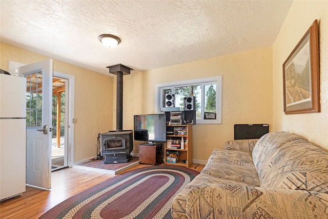 living room with a textured ceiling, hardwood / wood-style floors, and a wood stove