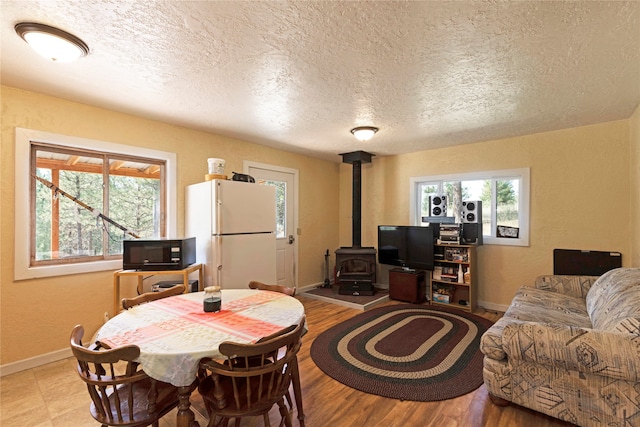 dining area with a textured ceiling, light hardwood / wood-style floors, and a wood stove