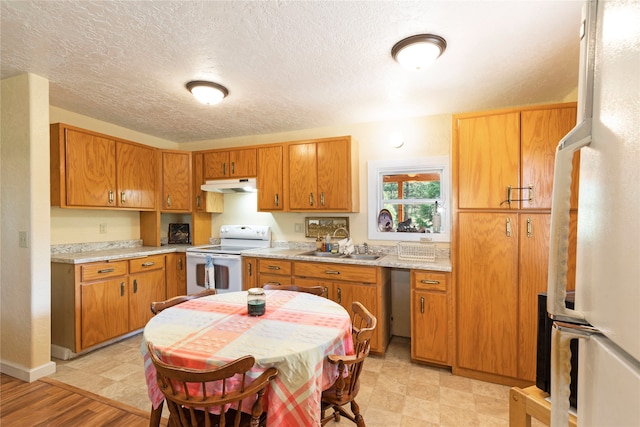 kitchen featuring sink, white appliances, light tile patterned floors, and a textured ceiling