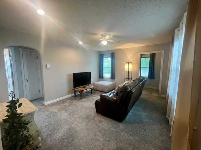 carpeted living room featuring a textured ceiling and ceiling fan