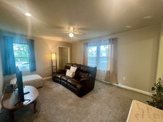 living room with ceiling fan, baseboard heating, carpet, and plenty of natural light