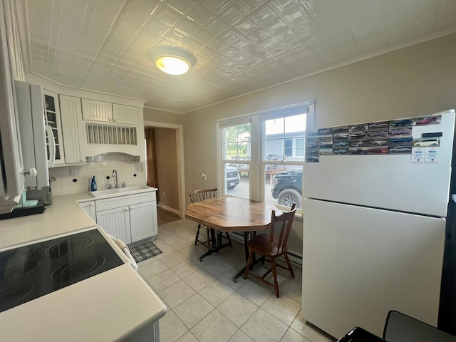 kitchen with white fridge, white cabinetry, decorative backsplash, sink, and stove