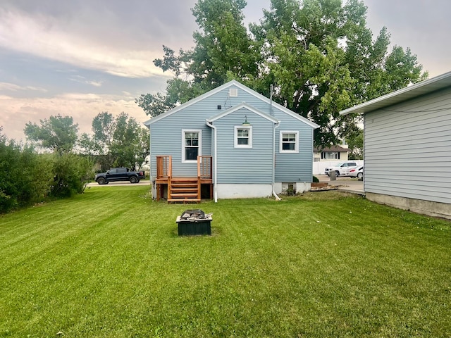 back house at dusk featuring a lawn