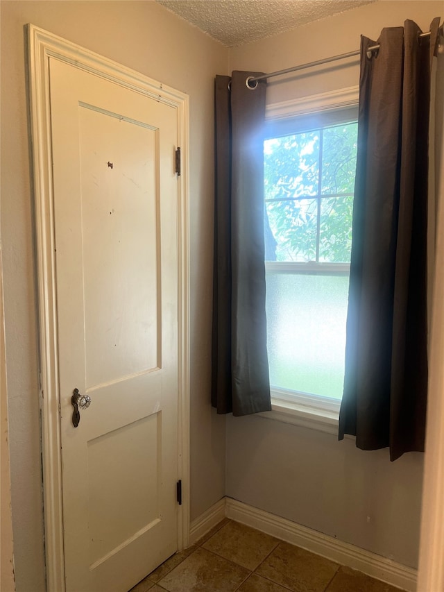 tiled spare room with a wealth of natural light and a textured ceiling