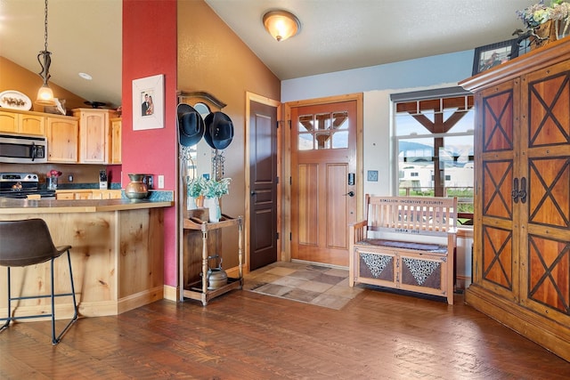 kitchen with vaulted ceiling, dark hardwood / wood-style floors, pendant lighting, a breakfast bar area, and stainless steel appliances