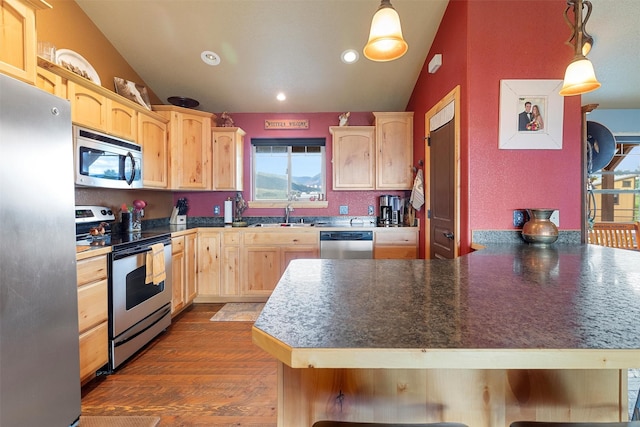 kitchen featuring decorative light fixtures, stainless steel appliances, a kitchen breakfast bar, and light brown cabinets