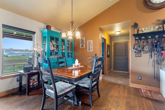 dining space with dark wood-type flooring, lofted ceiling, and a chandelier