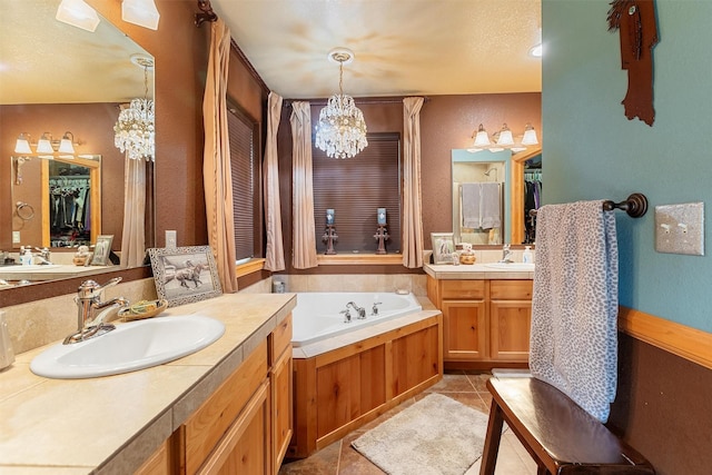 bathroom with an inviting chandelier, vanity, tile patterned floors, and a tub to relax in