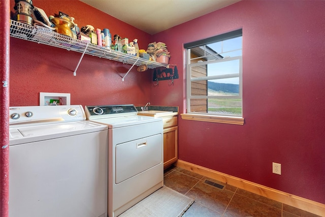 laundry room featuring cabinets, washer and clothes dryer, sink, and dark tile patterned floors