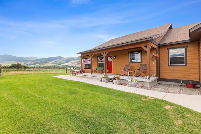 back of property with a rural view, a mountain view, a lawn, and a patio area